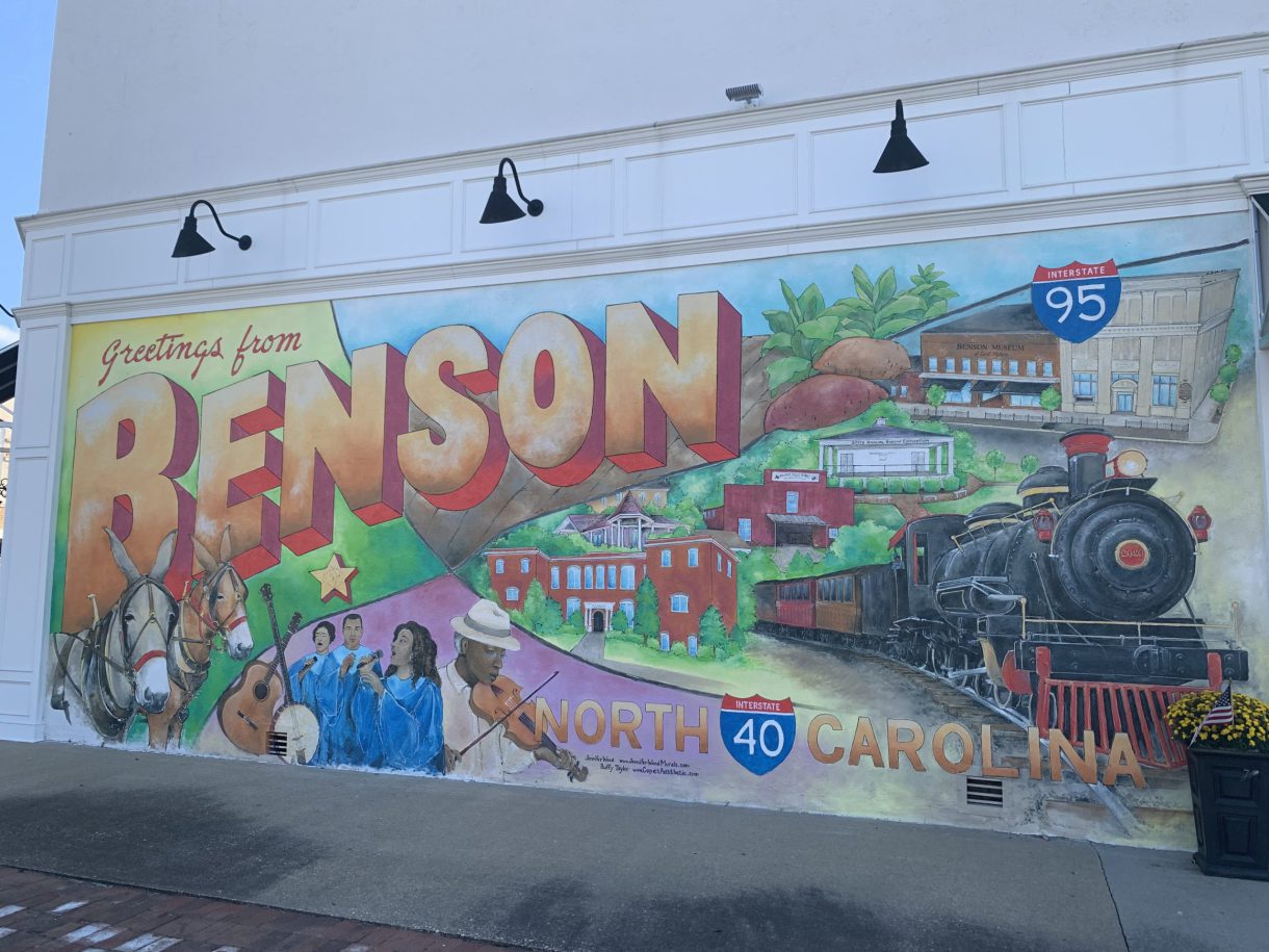 A Benson mural depicting civic buildings, a train, and Black musicians