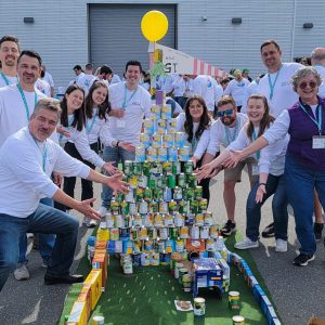 Employees gather around a miniature golf hole made from pantry items like canned food