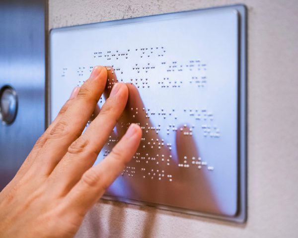 Close-up of a hand touching a placard in Braille