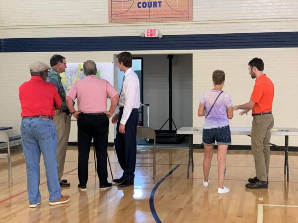 Adults standing at a meeting in a school gymnasium