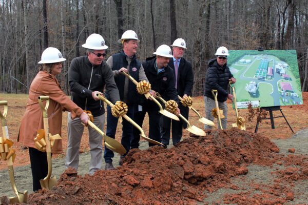 A group of people using golden shovels to ceremonially break ground on a project