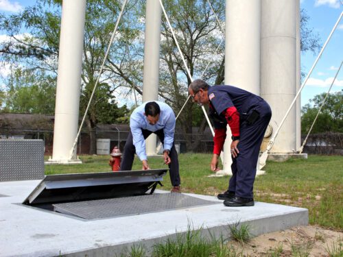 Two people bent over a access cover for an underground vault