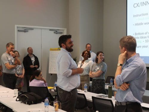 Professionals in a conference room laughing at a joke told by a presenter