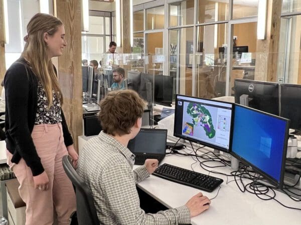 A high school student observing a planner at work on a coputer