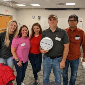 The winning team of a scavenger hunt holding a clock showing their completion time