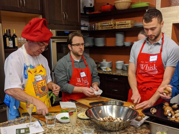 Three men in red aprons cooking
