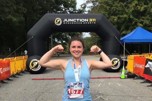 A young woman flexing her arm muscles at the finish line of a race