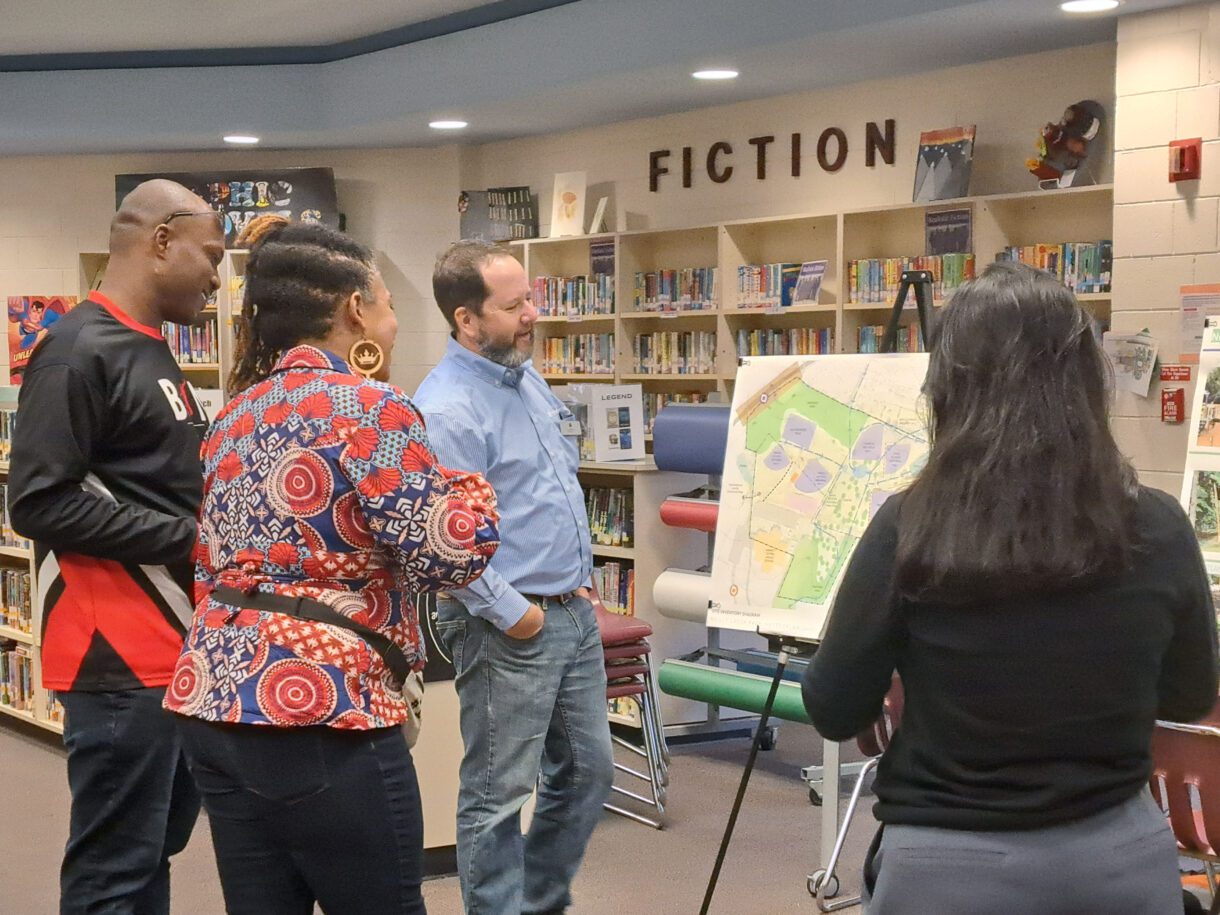 Adults gather around an easel showing a project map