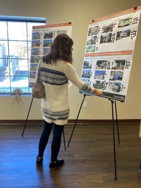 A woman at a public meeting reviewing design plans.