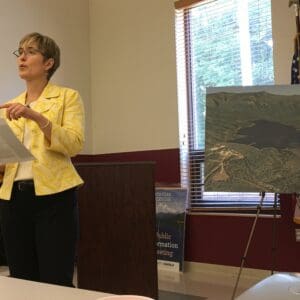 A public information leading with a woman at the front of the room talking to attendees.