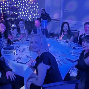 A group of formally dressed professionals sitting at a dining table at an awards banquet.