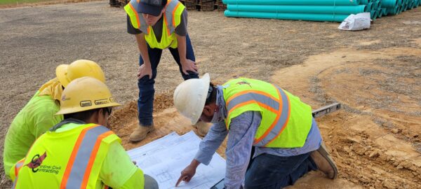 Staff professionals looking over plans at a construction site.