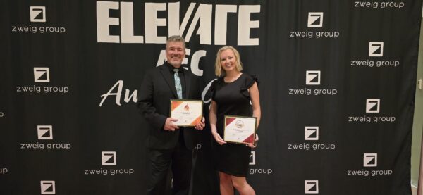 Two people receiving award certificates at a banquet.