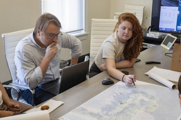 Members of the design and planning team looking over a map on a conference table.