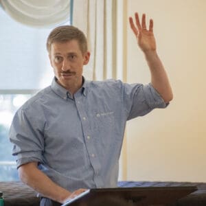 A speaker at an event raising their hand to gauge the audiences' reception.