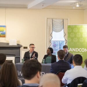 A picture looking at the panelists of an event speaking to a small crowd.