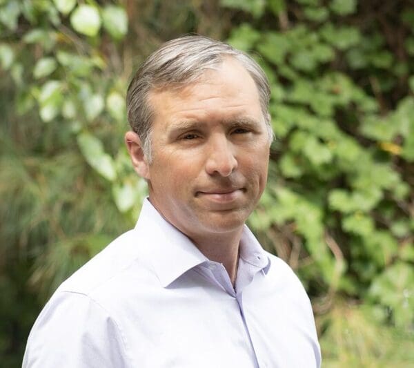 A headshot of an employee, waist up, and wearing a long sleeve shirt.