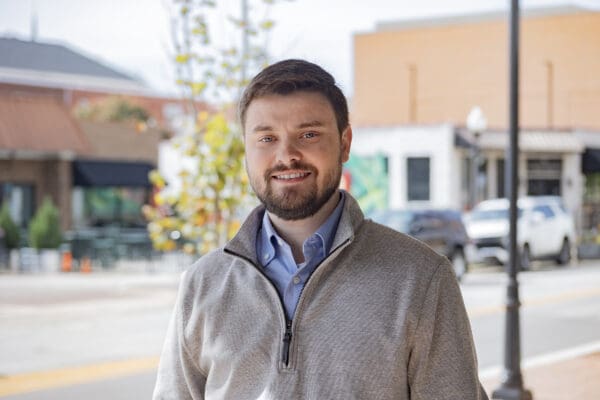 A headshot of a WithersRavenel employee standing in front of a downtown streetscape.