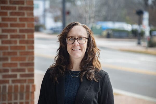 A headshot of a WithersRavenel employee standing adjacent to a brick column and a street is behind them.
