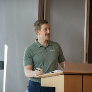 A moderator speaking at a podium in a conference room.