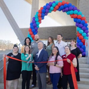 A group of people cut a large ribbon in front of the new Chatham Park YMCA