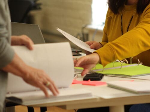 Two female business professionals organizing binders with business information.