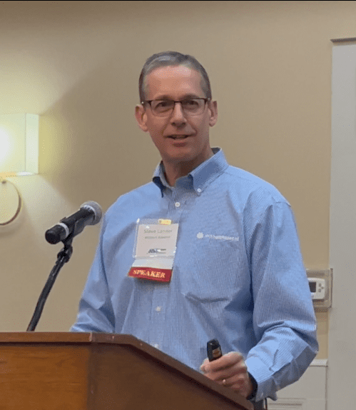 An image of Steve Lander presenting at a conference.