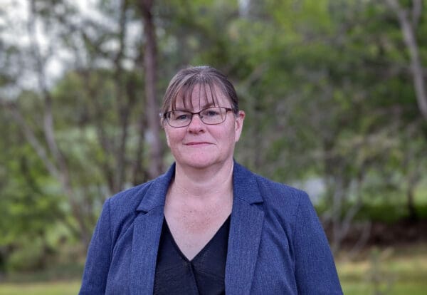 A woman with bangs and glasses wearing a blazer