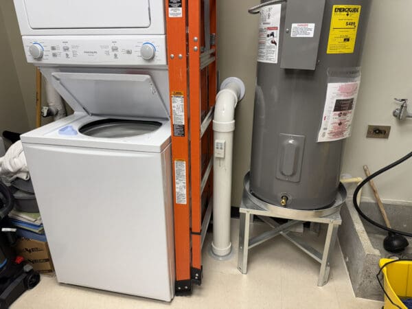 In a utility room between a washing machine and a water heater there is a PVC pipe with a 90 degree elbow in it that runs from the floor to the wall