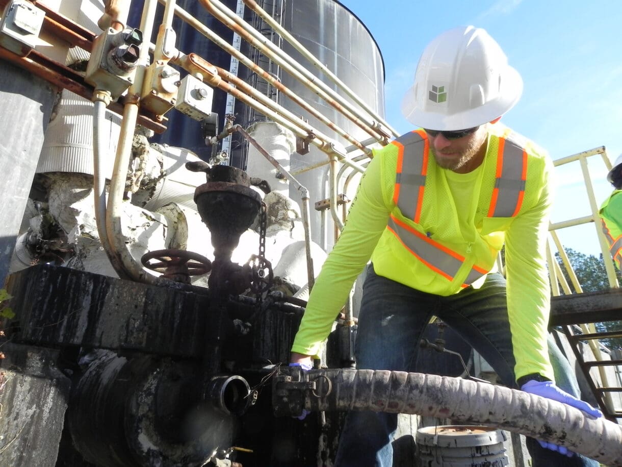 A man in a construction vest and helmet conducting a soil test.