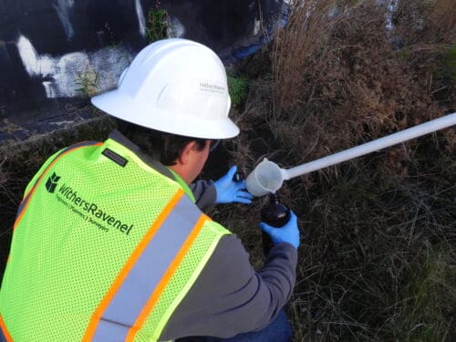 A man in a construction vest and helmet conducting a soil test.