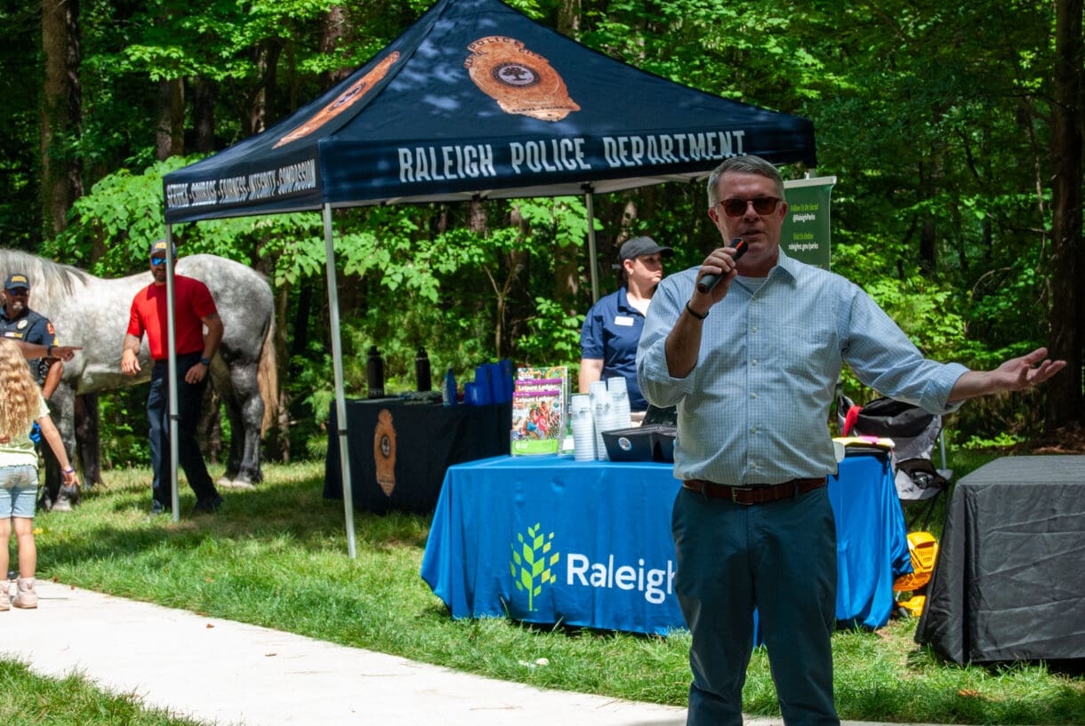 A man speaking to a group of park visitors.