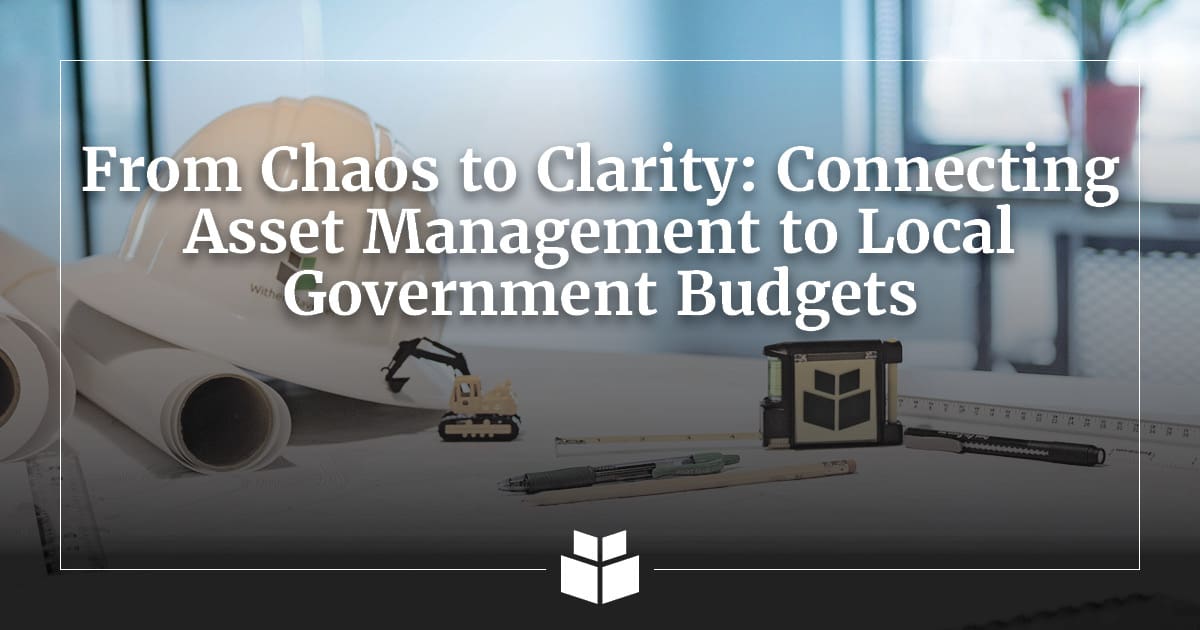 Rolled construction plans, surveying tools, and a miniature excavator on a desk beneath the title “From Chaos to Clarity: Connecting Asset Management to Local Government Budgets.”