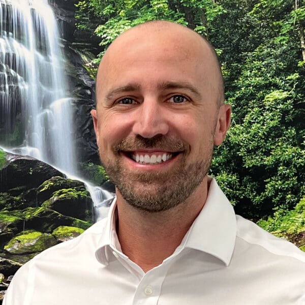 A smiling bald man with a mustache and beard in a white shirt