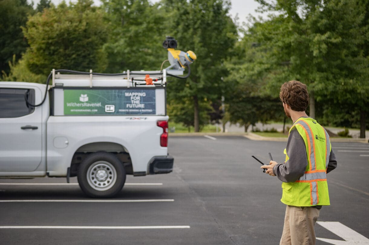 A man looking at a drone with a truck in the background.