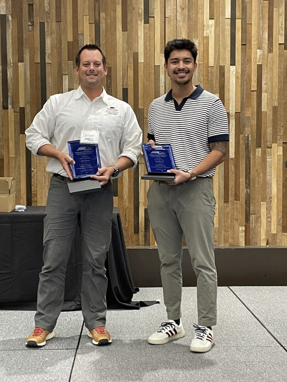 David Fishel of the City of New Bern and Antonio De Cecco of WithersRavenel stand together holding blue APWA-NC project awards.