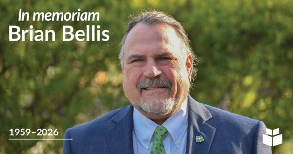Memorial graphic featuring a portrait of Brian Bellis in a blue suit and green tie against a softly blurred outdoor background. Text reads, “In memoriam Brian Bellis, 1959–2026.”