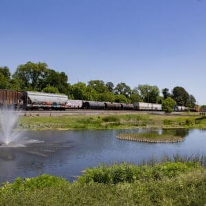 Biddle Street stormwater wet pond with a fountain and planted island beside an active rail corridor.