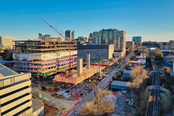 Aerial view of the Smoky Hollow development under construction in downtown Raleigh, with cranes, multistory buildings, streets, and a rail line.