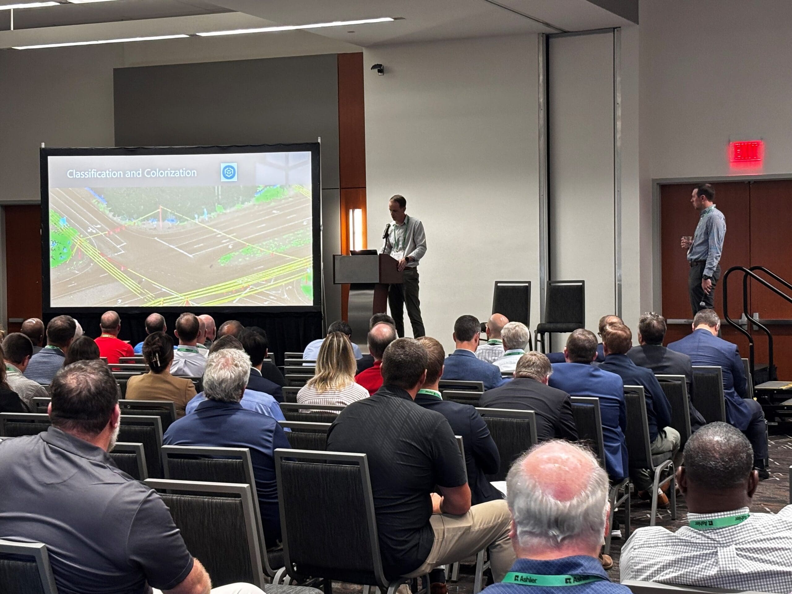 A screen displays a color-coded roadway intersection beside two presenters during WithersRavenel’s remote sensing session.