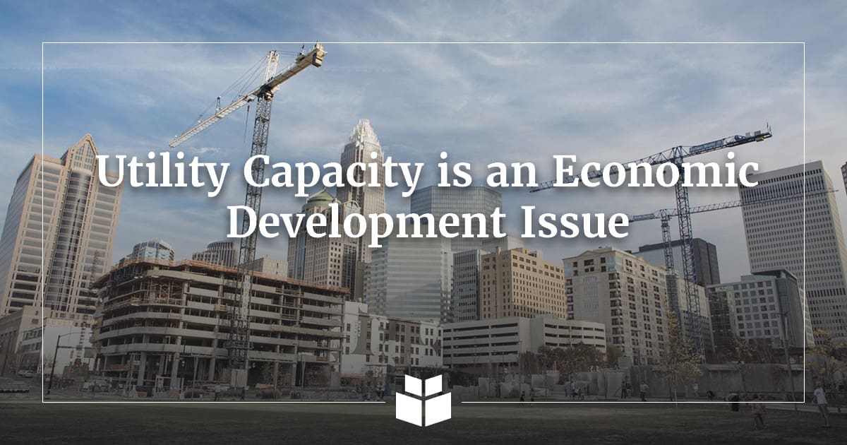Construction cranes and a partially completed building rise against the Charlotte skyline, with overlaid text reading “Utility Capacity is an Economic Development Issue” and the WithersRavenel logo.